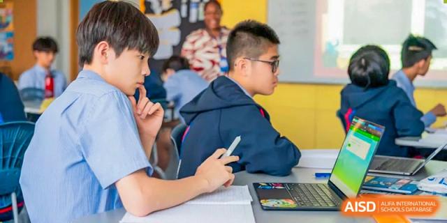 A male student wearing glasses and looking at his tablet during a class at Yew Chung International School of Shanghai.