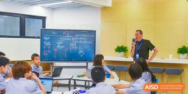 Students sitting at desks and watching a presentation on a large screen in a classroom at Yew Chung International School of Shanghai.