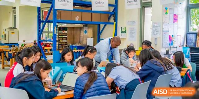A teacher helping a group of students working on a project in a classroom at Yew Chung International School of Shanghai.