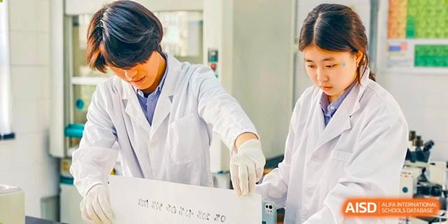 A student wearing a lab coat and gloves, working with a sheet of paper at Yew Chung International School of Shanghai.