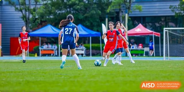 Female students playing soccer on a grassy field at Yew Chung International School of Shanghai.