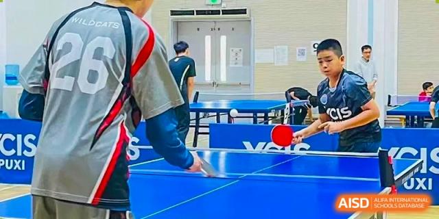 A student playing table tennis in a gym at Yew Chung International School of Shanghai.