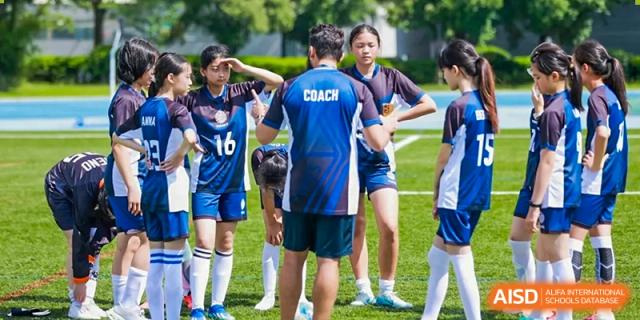 A coach talking to a group of female students in a team huddle at Yew Chung International School of Shanghai.