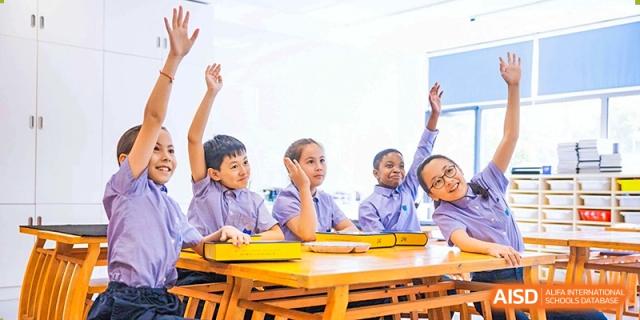 Elementary students raising their hands in a classroom at Yew Wah International Education School of Shanghai Lingang.
