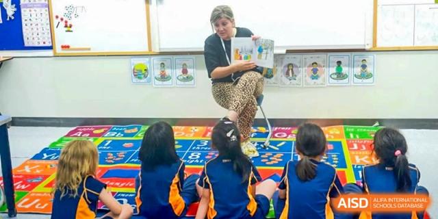 A teacher reading to a group of young students on a colorful rug at Yew Wah International Education School of Shanghai Lingang.