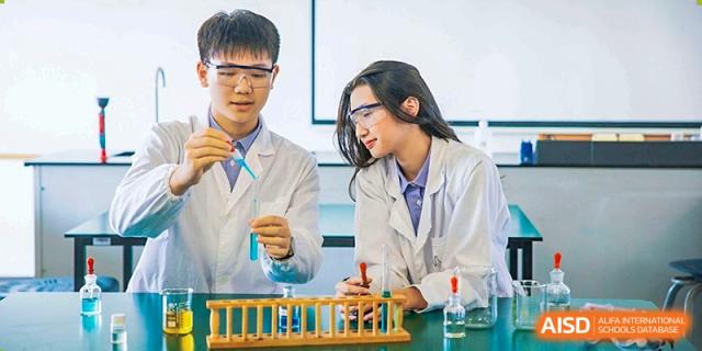 Students in lab coats performing a science experiment at Yew Wah International Education School of Shanghai Lingang.