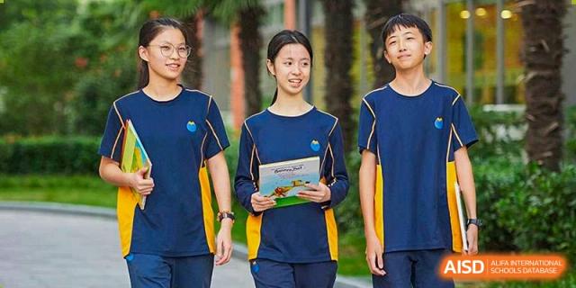 A smiling student holding a book while wearing a school uniform at Yew Wah International Education School of Shanghai Lingang.