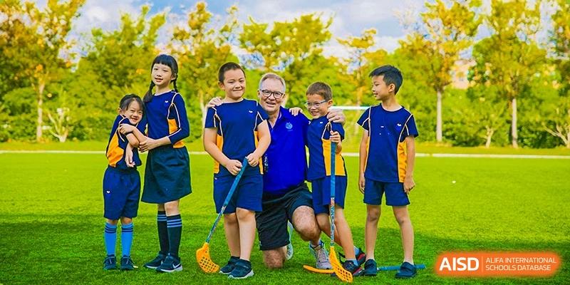 Students and a teacher playing floorball at Yew Wah International Education School of Shanghai Lingang.