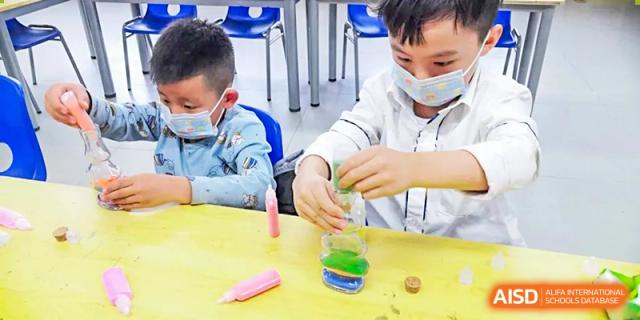 Young student wearing a face mask mixing colorful liquids in a science or art experiment at BIBA (Tianjin International Bilingual Academy).