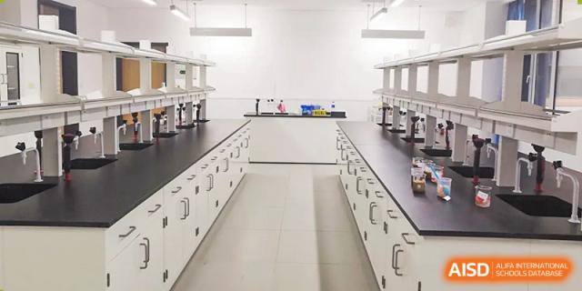 A clean, empty science laboratory featuring white lab benches, sinks, and storage cabinets at BIBA (Tianjin International Bilingual Academy).