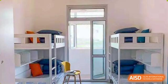 Dormitory room with bunk beds and a large window or glass door letting in light, showing student living accommodations at BIBA (Tianjin International Bilingual Academy).