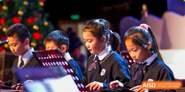 Students in uniform intently reading sheet music while performing in a dimly lit, indoor setting at BIBA (Tianjin International Bilingual Academy).
