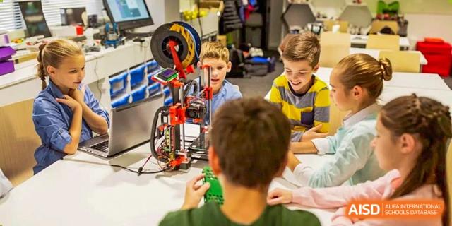 Young students from Dingwen Academy Hangzhou collaborating on building a large robotics or engineering model in a dedicated classroom.