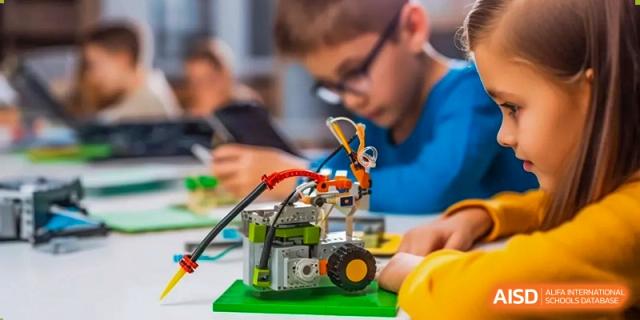 A close-up of a student from Dingwen Academy Hangzhou focused on building a small robot using yellow and black pieces.