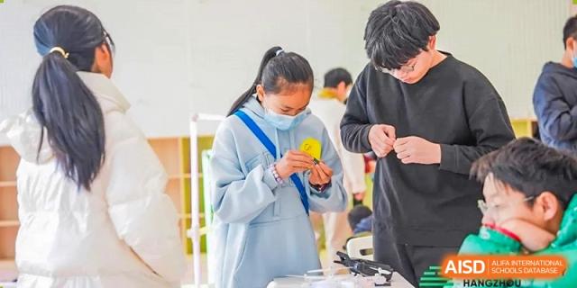 Two students from Dingwen Academy Hangzhou collaborating on a hands-on project in a bright workspace.
