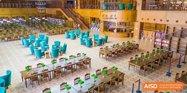 A high-angle view of the large, impressive library or study hall at Dingwen Academy Hangzhou, with many tables and blue chairs.