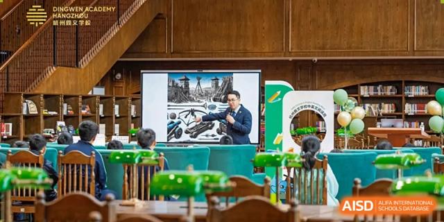 A teacher from Dingwen Academy Hangzhou giving a presentation to students in a lecture hall or classroom with a screen displaying architectural images.