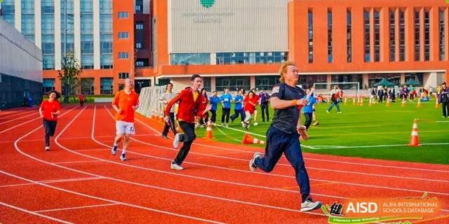 Students and adults from Dingwen Academy Hangzhou running on a red track during a race or practice session.