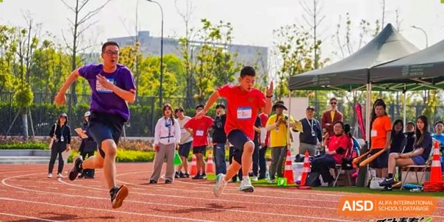 A student from Dingwen Academy Hangzhou running in a sprint event on a track during a sports day competition.