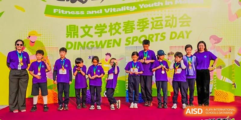 A group of students from Dingwen Academy Hangzhou posing with medals at the school's sports day event, with a banner in the background.