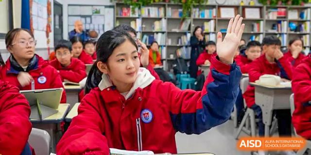 A female student from Henan Zhengzhou Jianye International School looking up in a library setting, with bookshelves visible in the background.