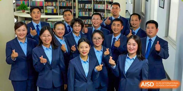 A large group of students from Henan Zhengzhou Jianye International School in uniform smiling and posing for a cheerful group photo.