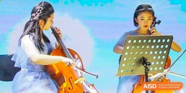 A close-up of a student from Henan Zhengzhou Jianye International School playing a string instrument, possibly a cello or violin, during a performance.