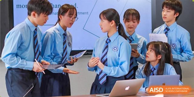 A small group of female students from International Department of Jinling High School Hexi Campus discussing a project or lesson, looking at a laptop and screen.