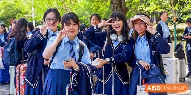 A group of female students from International Department of Jinling High School Hexi Campus smiling and posing outdoors on the campus grounds.