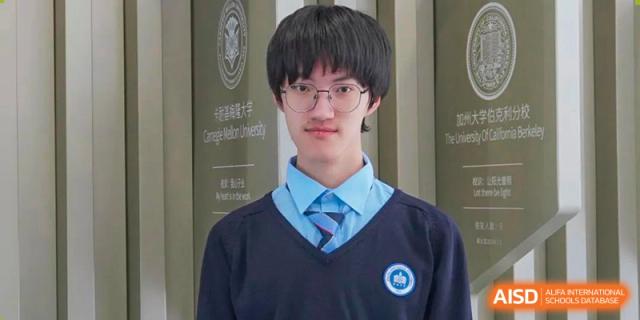 A portrait of a male student from International Department of Jinling High School Hexi Campus wearing a navy blue school uniform sweater and glasses, standing in front of a banner listing university names like Carnegie Mellon University.