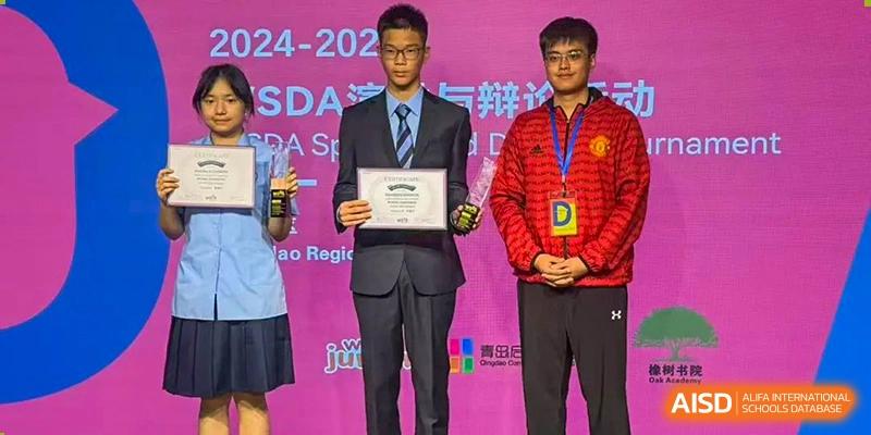 Two male students from International Department of Jinling High School Hexi Campus, one in a suit holding a certificate and the other in a red sports jacket, standing on a stage during an award ceremony.