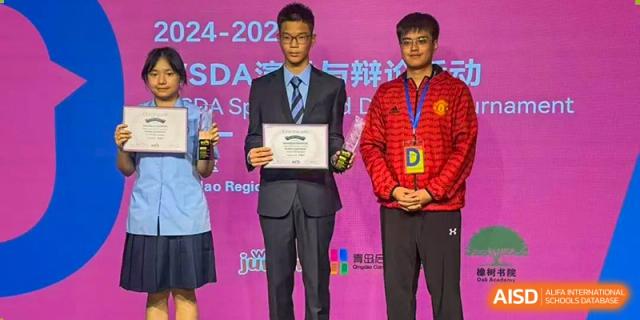 Two male students from International Department of Jinling High School Hexi Campus, one in a suit holding a certificate and the other in a red sports jacket, standing on a stage during an award ceremony.