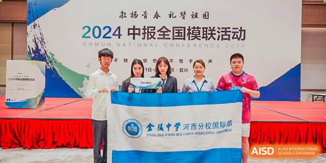 A small group of students and faculty from International Department of Jinling High School Hexi Campus holding a blue and white banner at a national conference or competition in 2024.