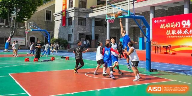 Students from the Guangdong Overseas Chinese High School International Curriculum playing a game of basketball on an outdoor court.