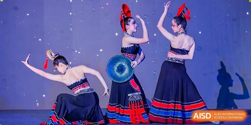 Two students from the Guangdong Overseas Chinese High School International Curriculum performing a traditional or cultural dance in dark costumes with fans.