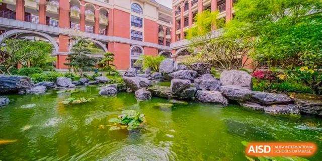 A close-up view of the serene rock garden and koi pond area on the campus of the Guangdong Overseas Chinese High School International Curriculum.