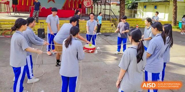 Students from the Guangdong Overseas Chinese High School International Curriculum participating in a team-building or outdoor activity involving props.