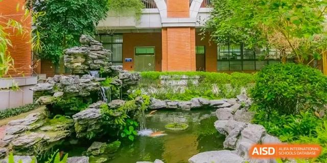 A wider view of the landscaped rock garden and pond area at the Guangdong Overseas Chinese High School International Curriculum.