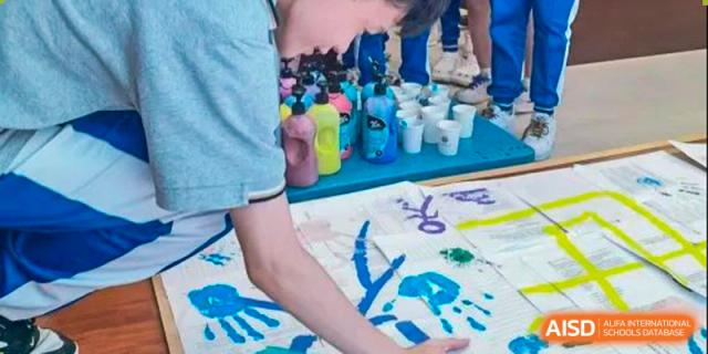 A close-up of students from the Guangdong Overseas Chinese High School International Curriculum participating in a hand-painting or arts and crafts activity.