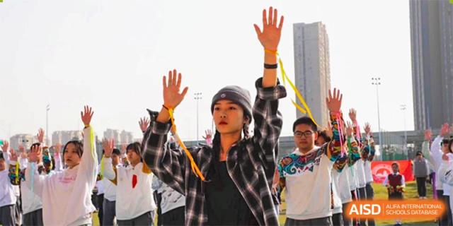 A Wuhan Weiming Senior High School student raising their hands in enthusiasm or protest during an outdoor school event or rally.