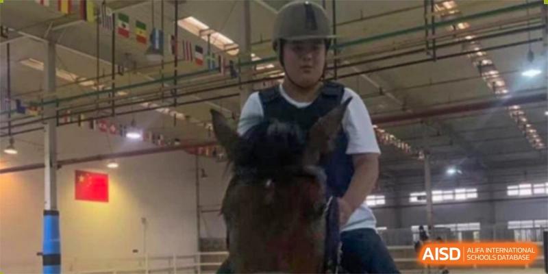 A Wuhan Weiming Senior High School student wearing a helmet while horseback riding during a school activity or lesson.