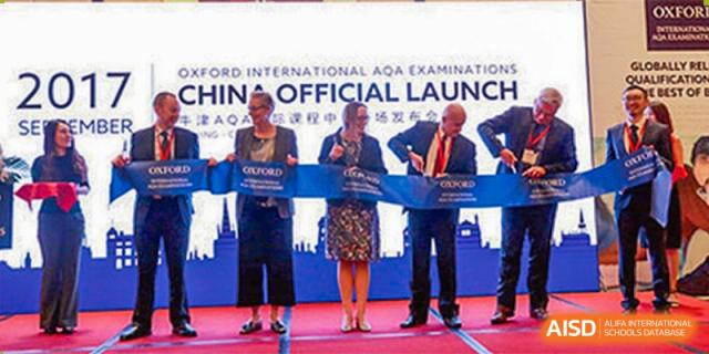 Wuhan Weiming Senior High School teachers and administrators attending an "Official Launch" ceremony on stage with a banner.