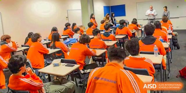 A large class of Wuhan Weiming Senior High School students wearing bright orange uniforms attending a lecture or training session.