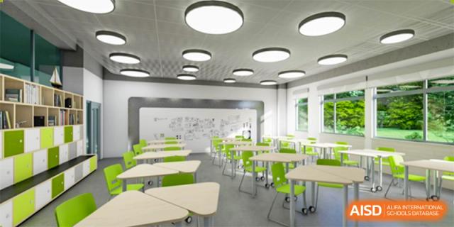 An empty, brightly lit classroom at Wuhan Weiming Senior High School featuring modern desks and bright green chairs.
