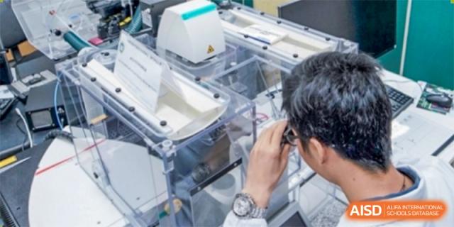 A Wuhan Weiming Senior High School student working with specialized laboratory equipment or a machine, wearing safety glasses.
