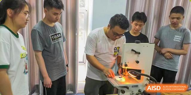 An instructor or student at Wuhan Weiming Senior High School focused on working with a sewing machine in a practical skills class.