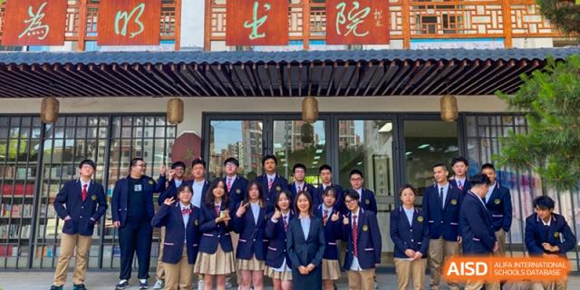 A group of smartly dressed Wuhan Weiming Senior High School students in uniform posing together beneath a traditional-style building entrance.