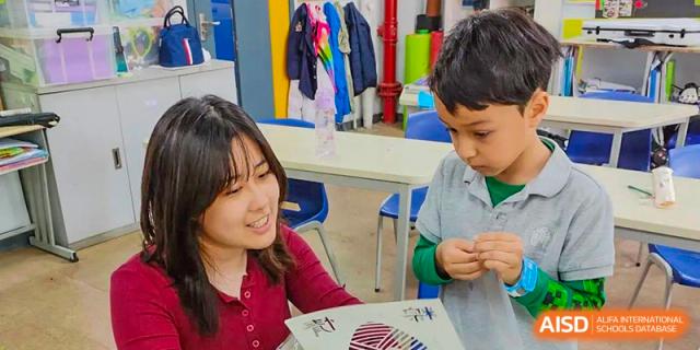 A female teacher helping a young male student with a drawing activity at the Shanghai Jincai High School International Division.