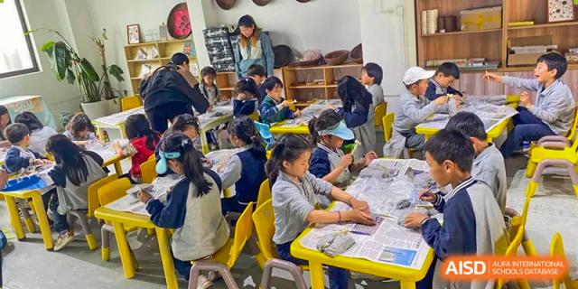 Young students sitting around a table working on a craft project together at the Shanghai Jincai High School International Division.