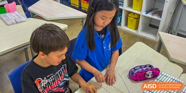 A young female student working on a craft project with other students at the Shanghai Jincai High School International Division.